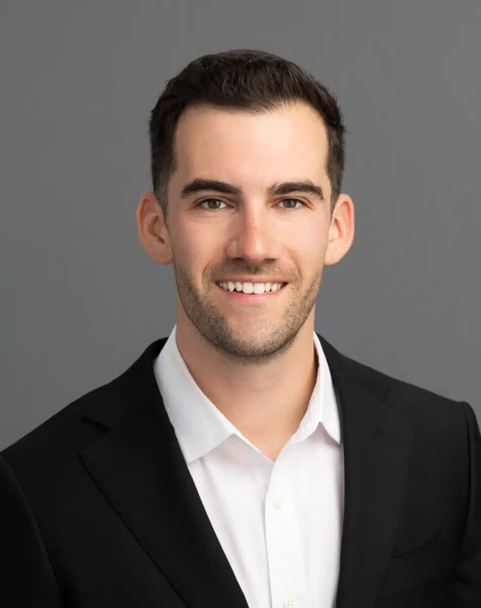 a man wearing a suit and tie smiling and looking at the camera